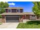 Home with a brick and siding exterior, a two-car garage, and vibrant landscaping, set against a blue sky at 6062 S Newport St, Centennial, CO 80111