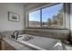 A luxurious soaking tub with stylish fixtures and serene views from the large window at 5371 Hazel Rd, Evergreen, CO 80439