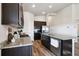 Bright kitchen featuring an island, stainless appliances, dark cabinets, and hardwood flooring at 98 Chipeta Way, Lochbuie, CO 80603