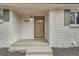 A light wood front door with a glass window inset and a painted white brick facade at 9455 W 37Th Ave, Wheat Ridge, CO 80033