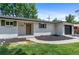 Beautiful, renovated single-story house with white brick, green shutters, updated landscaping and a stained, wood front door at 9455 W 37Th Ave, Wheat Ridge, CO 80033