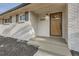 Front entrance with stained wood door, white brick, modern exterior light, and black mulch landscaping at 9455 W 37Th Ave, Wheat Ridge, CO 80033