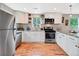 Modern kitchen featuring white cabinets, stainless steel appliances, and hardwood floors at 6245 W 53Rd Ave, Arvada, CO 80002