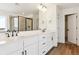 Well-lit bathroom with double sinks, white cabinetry, and black hardware; a glass shower is also visible at 8346 Cokedale Cir, Littleton, CO 80125
