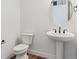 Clean powder room featuring white fixtures, including a pedestal sink, toilet, and minimalist decor at 8346 Cokedale Cir, Littleton, CO 80125