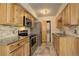 Modern kitchen with stainless steel appliances and wooden cabinets next to a laundry closet at 1820 Newland Ct # 213, Lakewood, CO 80214