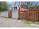 Exterior view of garages and a wooden gate and fence in the alley behind a brick building at 1545 Steele St, Denver, CO 80206