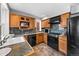 Functional kitchen featuring wood cabinetry, black appliances, and durable tile flooring at 1545 Steele St, Denver, CO 80206