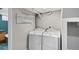 Laundry room with modern washer and dryer units, shelving for storage, and utility connections at 1545 Steele St, Denver, CO 80206