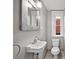 Compact powder room featuring a vintage-inspired mirror and a classic pedestal sink at 1545 Steele St, Denver, CO 80206