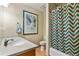 Clean bathroom with a shower/tub combo, modern vanity, stylish mirror, and eye-catching chevron shower curtain at 2957 W Rowland Ave, Littleton, CO 80120
