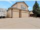 Tan two-story home featuring a spacious driveway and a two-car garage with brick accents at 2957 W Rowland Ave, Littleton, CO 80120