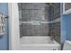 Bathtub with white tile walls with blue accents and a shower head at 1153 S Biscay St, Aurora, CO 80017