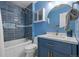 Bright bathroom featuring a blue vanity with marble countertop, tub with blue tile and a round mirror at 1153 S Biscay St, Aurora, CO 80017