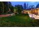 Landscaped backyard with lush green lawn, garden beds, hot tub, and covered patio at 250 S Dahlia St, Denver, CO 80246