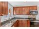 Well-lit kitchen featuring brown cabinets, granite countertops, and stainless steel appliances at 2738 Xanadu St, Aurora, CO 80011