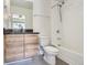 Bathroom featuring a vanity with a black countertop, toilet, and shower over tub with white tiled walls at 5530 W 11Th Pl, Lakewood, CO 80214