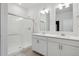 Bright bathroom features a double vanity with white cabinets and a glass-enclosed tiled shower at 6501 14Th St, Frederick, CO 80530
