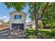 Two-story home has an attached garage and a tree in the front yard at 6303 W Exposition Ave, Lakewood, CO 80226