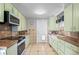 Traditional kitchen with stainless appliances, tile floor, and green cabinetry for ample storage at 6303 W Exposition Ave, Lakewood, CO 80226