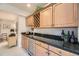 Elegant bar area with dark granite countertops, wooden cabinets, and a wine fridge for storing beverages at 11070 Meade Ct, Westminster, CO 80031
