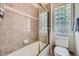 Bathroom features tiled walls, a bathtub with a glass partition, and a glass block window for privacy at 11070 Meade Ct, Westminster, CO 80031