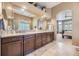 Bathroom vanity with double sinks, stone countertops, dark wood cabinets, and travertine flooring at 11070 Meade Ct, Westminster, CO 80031