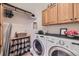 Functional laundry room features front loading washer and dryer, storage cabinets and an ironing board at 11070 Meade Ct, Westminster, CO 80031