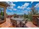 Outdoor deck with stone and iron railing featuring a table, chairs, and stunning views at 28800 Stonecrop Trl, Conifer, CO 80433