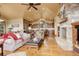 Open-concept living area featuring a stone fireplace, wood floors, and seamless kitchen access at 28800 Stonecrop Trl, Conifer, CO 80433