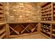 Cozy wine cellar featuring custom shelving, brick flooring and decorative stone wall at 28800 Stonecrop Trl, Conifer, CO 80433
