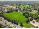 Aerial view of a park and pond in a neighborhood surrounded by mature trees and lush greenery at 11578 Clayton St, Thornton, CO 80233