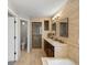 This bathroom features a double sink vanity, shower, soaking tub and lots of tile at 11578 Clayton St, Thornton, CO 80233
