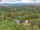 Scenic aerial view of a home with a detached garage, nestled among lush trees at 28858 Richmond Hill Rd, Conifer, CO 80433