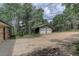 Home exterior showcasing the two-car garage, gravel driveway, stone accents, and lush surrounding trees at 28858 Richmond Hill Rd, Conifer, CO 80433