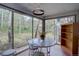 Bright sunroom features a marble table, decorative lighting, and walls of windows with views of the wooded property at 28858 Richmond Hill Rd, Conifer, CO 80433