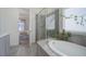 Bright bathroom with a soaking tub and a glass-enclosed shower, doorway to bedroom visible at 9750 Taylor River Cir, Littleton, CO 80125