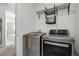 Modern laundry room with front loading washer and dryer and open shelving for storage at 9750 Taylor River Cir, Littleton, CO 80125
