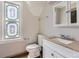 Bathroom featuring a stylish stained-glass window, white vanity, and matching toilet at 347 Bannock St, Denver, CO 80223