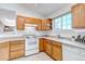 Functional kitchen boasting wood cabinetry, white appliances, and a bright window that allows for natural light at 18384 E Bethany Pl, Aurora, CO 80013