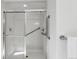 Modern shower with glass doors, white tiled walls, built-in shelving, and grab bars for accessibility, ensures safe bathing at 18384 E Bethany Pl, Aurora, CO 80013