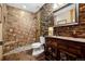 Rustic bathroom featuring stone wall, tiled shower, and wooden vanity with a decorative mirror at 5261 Sedona Dr, Parker, CO 80134