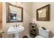 Stylish powder room featuring a pedestal sink, decorative mirror, and elegant fixtures at 3080 Big Bear Dr, Sedalia, CO 80135