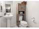 Stylish half bath with a pedestal sink, wooden storage cabinet, and contemporary fixtures at 5744 Alton St, Denver, CO 80238