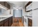 Well-lit kitchen with a view of the living room featuring white appliances and dark cabinetry at 6505 Kalua Rd # 204B, Boulder, CO 80301