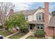 Charming townhome with well-manicured lawn, mature trees and a brick chimney under a partly cloudy sky at 9620 W Chatfield Ave # D, Littleton, CO 80128