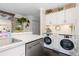 Bright laundry area featuring white cabinets, modern washer/dryer, and marble countertops at 9620 W Chatfield Ave # D, Littleton, CO 80128
