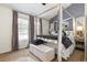 Bedroom with canopy bed, neutral carpet, and large window with decorative curtains at 9620 W Chatfield Ave # D, Littleton, CO 80128