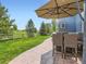 Backyard with a stone patio, an umbrella-covered dining set, and a lush lawn for outdoor enjoyment at 2896 Gemini Loop, Broomfield, CO 80023