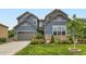 Charming exterior view showcasing the home's architectural details, lush landscaping, and attached two-car garage at 2896 Gemini Loop, Broomfield, CO 80023